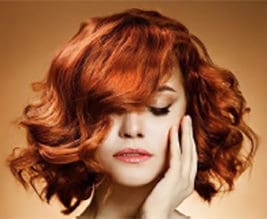A woman with red hair is holding her head.