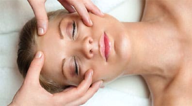 A woman getting her face washed with lotion.